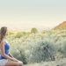 A woman in casual attire sits peacefully, enjoying a scenic outdoor view of nature.